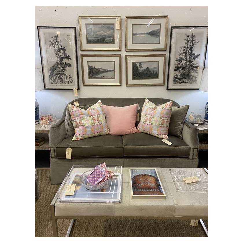 Licing room vignette with pink colored throw pillows, wall decor, and furniture